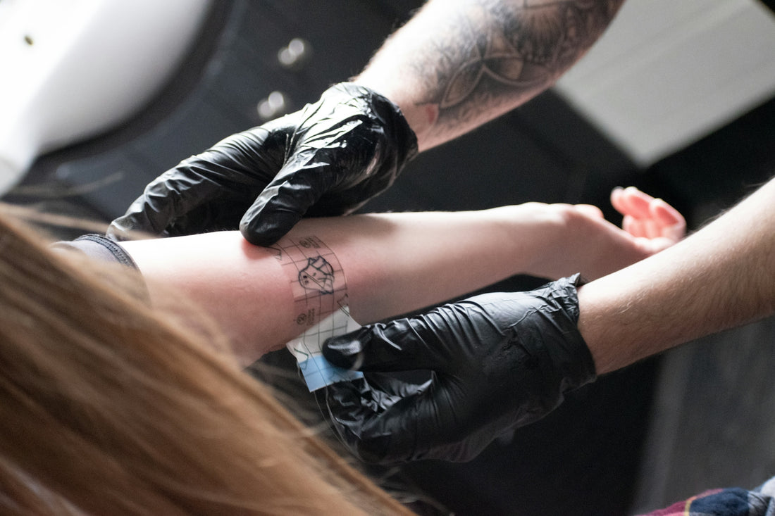 A tattoo artist is giving a tattoo.