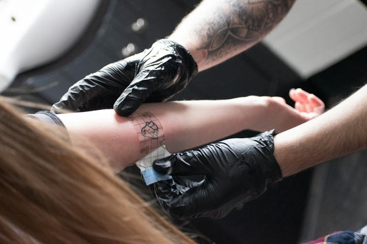 A tattoo artist is giving a tattoo.