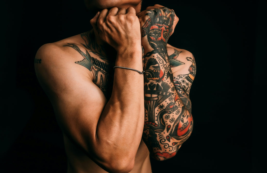 Man with fully tattooed arms against black background